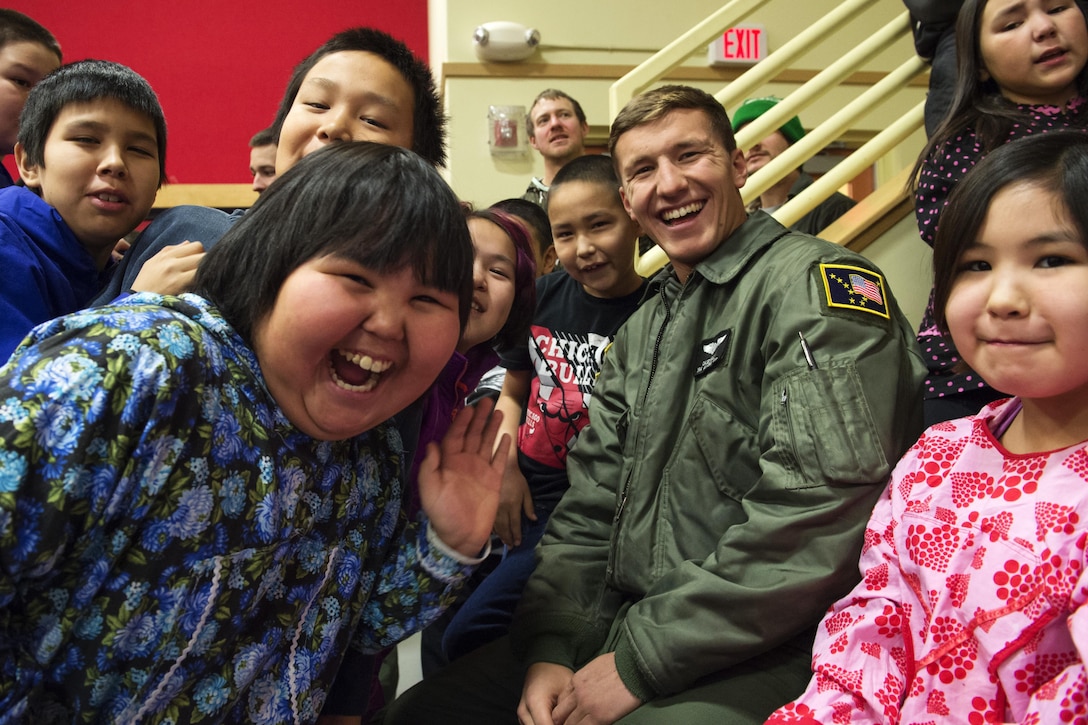 Alaska Air National Guard Senior Airman Casey Hill and elementary school students from St. Mary's, Alaska, smile for the camera during Operation Santa Claus, Dec. 5, 2015. U.S. Air Force photo by Alejandro Pena