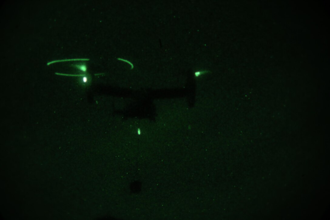 An MV-22B Osprey, operated by a crew with Marine Medium Tiltrotor Training Squadron 204, carries cargo during a night time external lifts operation at Camp Lejeune, N.C., Dec. 14, 2015. Marines with 2nd Transportation Support Battalion supported the exercise to facilitate the required flight hours for  student pilots, and practice their own skills as a helicopter support team securing transportation of resources for Marines that would need it in a real-world operation. (U.S. Marine Corps photo by Cpl. Paul S. Martinez/Released)