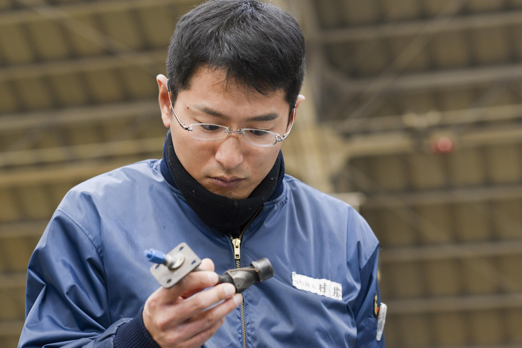 Japan Maritime Self-Defense Force Petty Officer 2nd Class Takeshi Murai, 4 Maintenance Squadron, inspects the part of a C-130 Hercules engine during a facility tour at Yokota Air Base, Japan, Dec. 11, 2015. Nine JMSDF members visited Yokota to learn about C-130 Hercules maintenance conducted at Yokota. (U.S. Air Force photo by Staff Sgt. Cody H. Ramirez/Released)