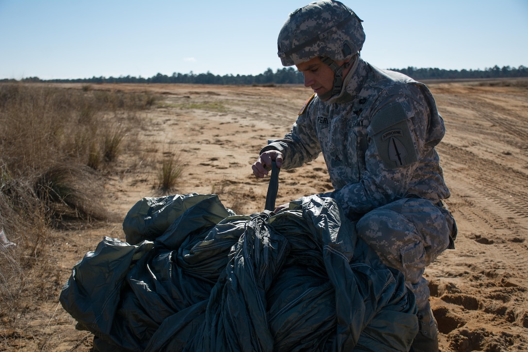 U.S. Army Sgt Juan Perez packs his parachute after an airborne operation during Operation Toy Drop at Luzon drop zone on Fort Bragg, N.C., Dec. 8, 2015. Operation Toy Drop is the world’s largest combined airborne operation with seven partner-nation paratroopers participating and allows airborne personnel the opportunity to earn partner-nation jump wings. U.S. Army photo by Pfc. Darion Gibson