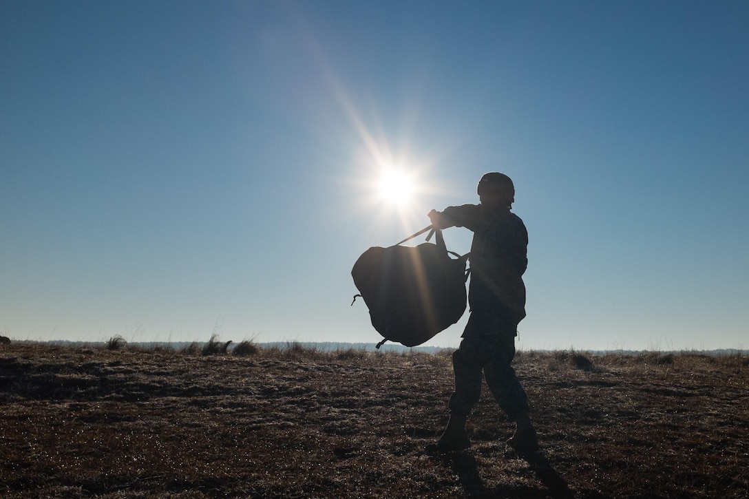 An Army paratrooper slings his parachute onto his back after a successful jump during the Randy Oler Memorial Operation Toy Drop over Sicily drop zone on Fort Bragg, N.C., Dec. 5, 2015. U.S. Army photo by Timothy L. Hale