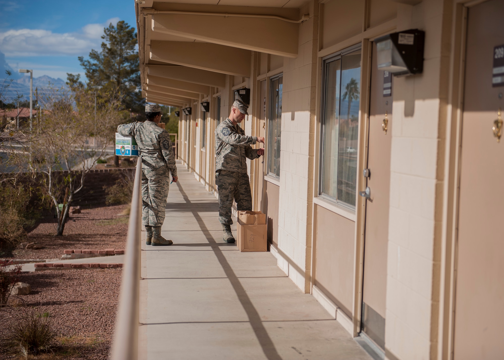 Master Sgt. Ira Jack, 57th Aircraft Maintenance Squadron first sergeant, and Senior Master Sgt. Christopher McEwan, 99th Security Forces Squadron first sergeant, deliver cookies to Airmen living in the dorms during the Airman Cookie Drive at Nellis Air Force Base, Nev., Dec. 14, 2015. During the cookie drive, people and organizations in the Nellis AFB community came together to give Airmen a taste of home during the holidays. (U.S. Air Force photo by Staff Sgt. Siuta B. Ika)