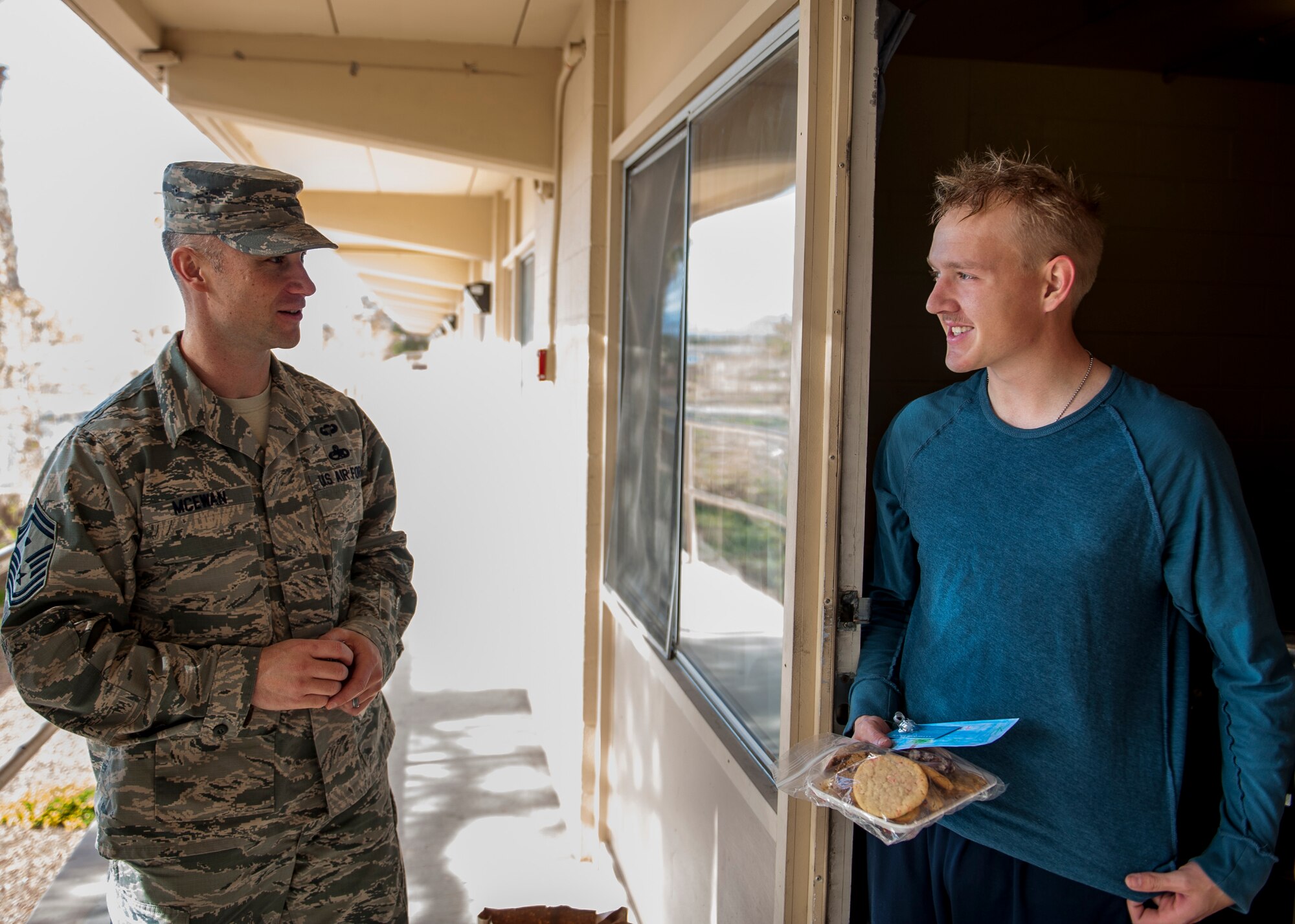 Airman 1st Class Hayden Woodcox, 99th Security Forces Squadron member, receives a cookie package from Senior Master Sgt. Christopher McEwan, 99th SFS first sergeant, during the Airman Cookie Drive at Nellis Air Force Base, Nev., Dec. 14, 2015. The cookie drive is held every year to show Airmen living in the Nellis AFB dormitories they are not forgotten during the holiday season. (U.S. Air Force photo by Staff Sgt. Siuta B. Ika)