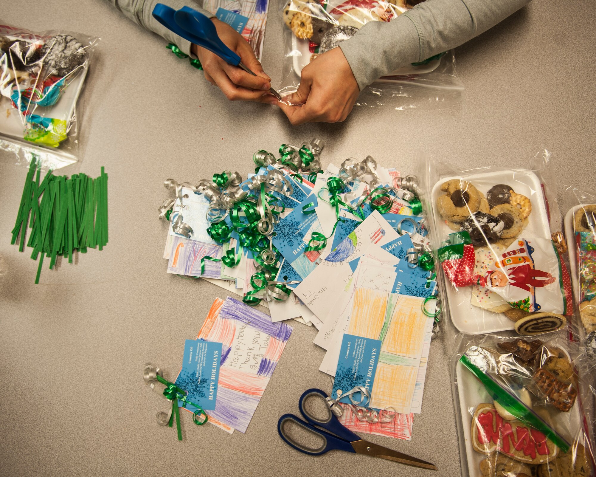 A volunteer preps a cookie package to have a ribbon and card attached to it during the Airman Cookie Drive at Nellis Air Force Base, Nev., Dec. 14, 2015. The cards were handmade by elementary school students in the local area. (U.S. Air Force photo by Staff Sgt. Siuta B. Ika)