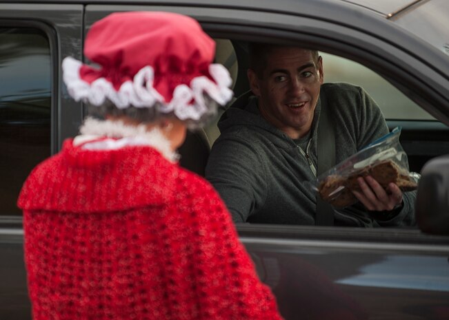 A donator to the Airman Cookie Drive hands over a bag of homemade cookies during the cookie drive’s drop off at the chapel on Nellis Air Force Base, Nev., Dec. 14, 2015. After cookies were collected, volunteers packaged them up and delivered them to Airmen living in the Nellis AFB dormitories. (U.S. Air Force photo by Staff Sgt. Siuta B. Ika)