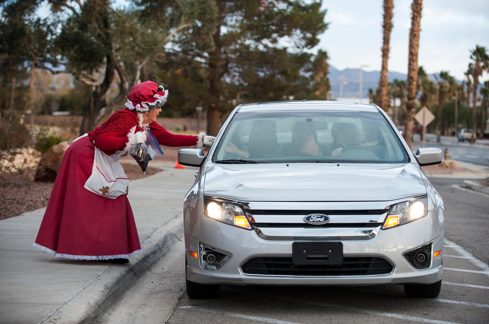 Margie Manning (left), a volunteer in the Airman Cookie Drive, collects cookies from a driver during the cookie drive’s drop off at the chapel on Nellis Air Force Base, Nev., Dec. 14, 2015. The Airman Cookie Drive is an annual event where Airmen living in Nellis AFB dormitories receive cookies and other homemade treats as a way to say thank you for the work they provide throughout the year. (U.S. Air Force photo by Staff Sgt. Siuta B. Ika)