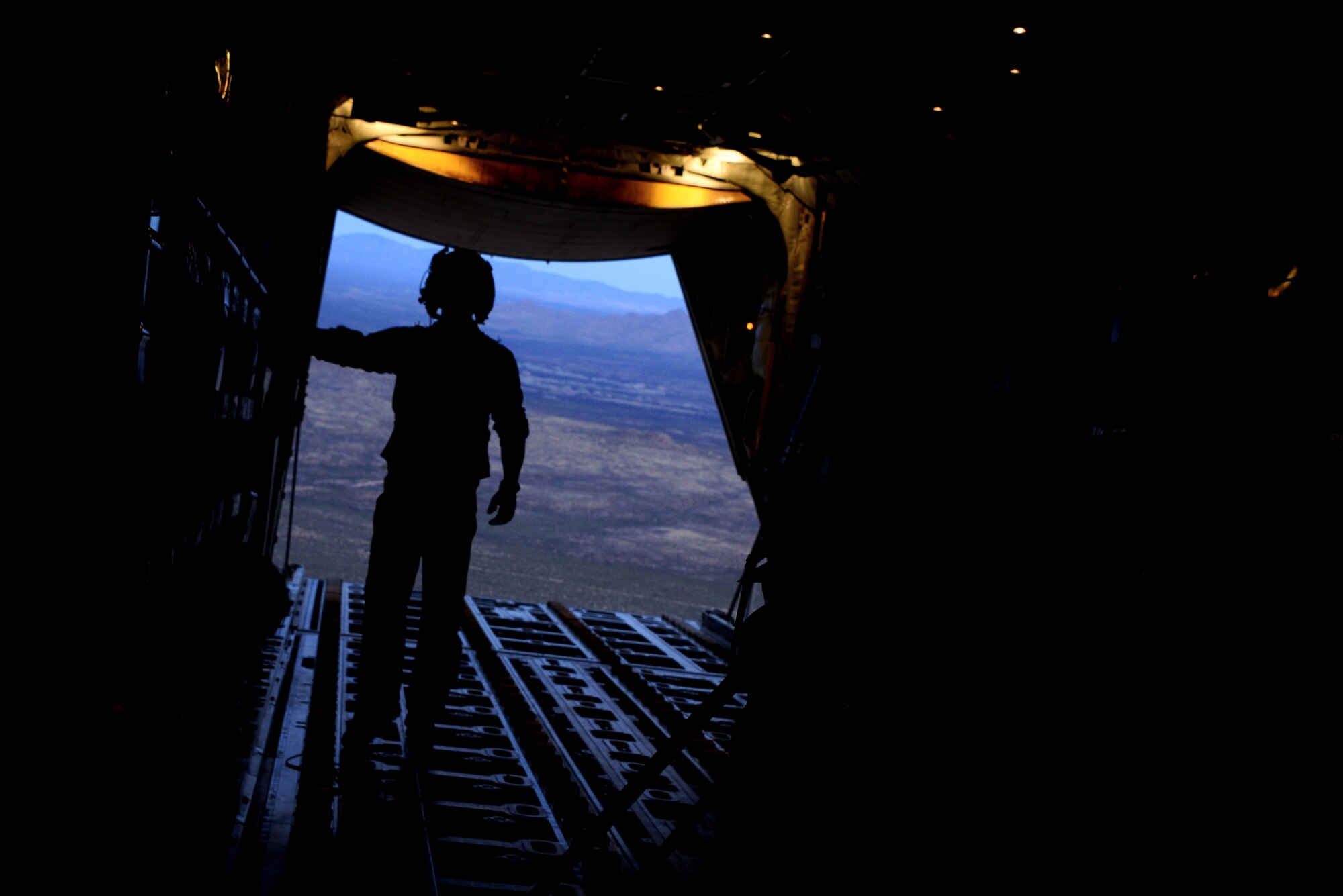 U.S. Air Force Staff Sgt. Russell Bickel, 79th Rescue Squadron loadmaster, monitors a drop from an HC-130J Combat King II during aerial delivery and recovery training with the 563rd Operations Support Squadron while flying over Fort Huachuca, Ariz., Dec. 9, 2015. Airdrops of heavy equipment and vehicles are emergent capabilities among Air Force personnel recovery forces to recover isolated personnel and deliver combat power throughout a large theater. (U.S. Air Force photo by Airman 1st Class Mya M. Crosby/Released)