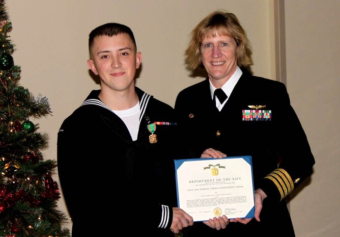 Seaman Colby Johnson, a general hospital corpsman serving at Naval Health Clinic Charleston, receives a Navy and Marine Corps Achievement from NHCC Commanding Officer Capt. Elizabeth Maley Dec. 4 at the clinic. Johnson was honored for saving the life of a baby who lost consciousness while choking Halloween night at Joint Base Charleston – Weapons Station. (Navy photo/ Petty Officer 3rd Class Robert Jackson)