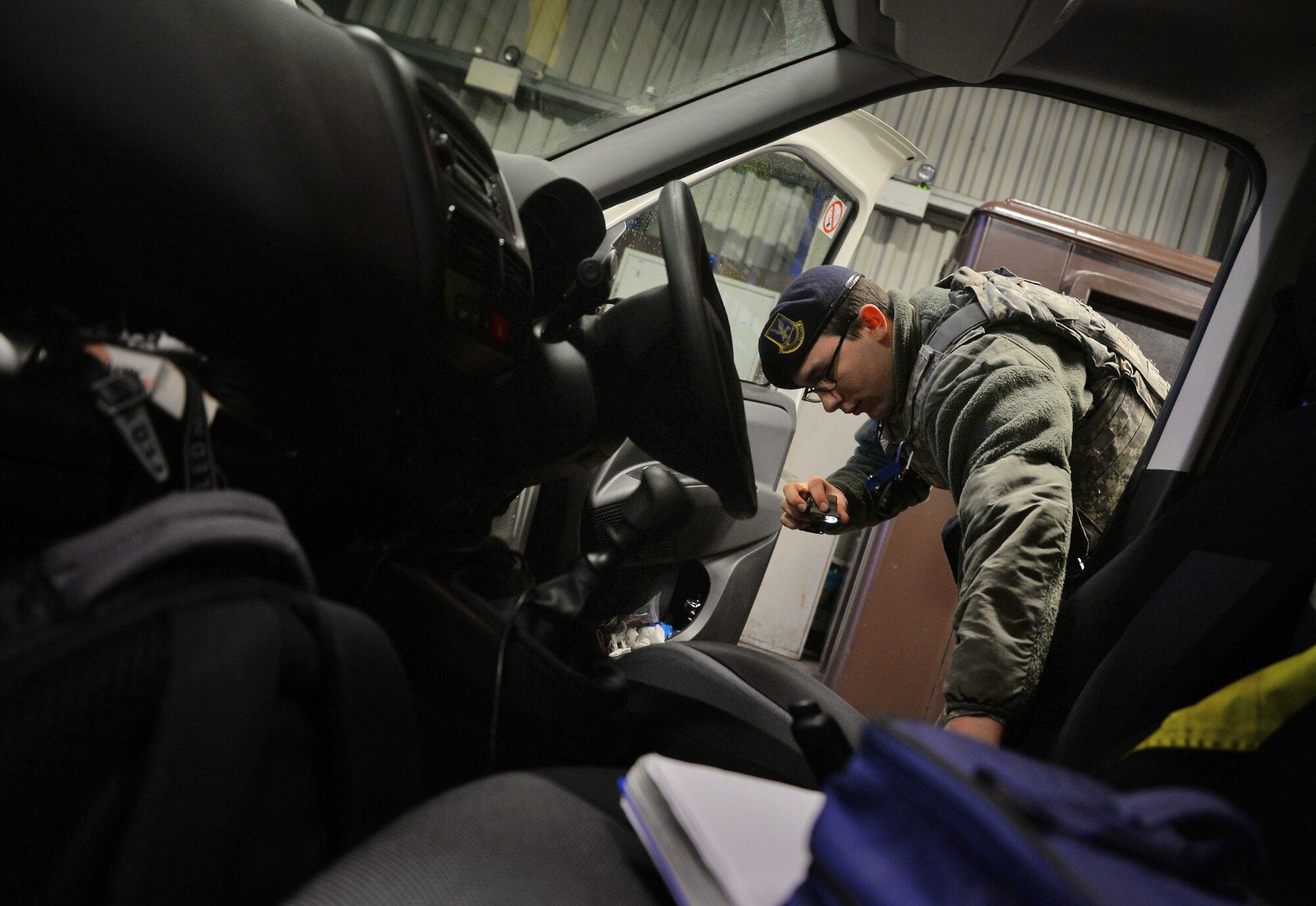 U.S. Air Force Airman Ryan Griffith, 100th Security Forces Squadron response force leader, inspects a vehicle Dec. 15, 2015, at the search barn on RAF Mildenhall, England. Both an armed Airman and a Ministry of Defence Guard Service civilian security officer are required to be in attendance during a vehicle inspection. (U.S. Air Force photo by Senior Airman Christine Halan/Released)