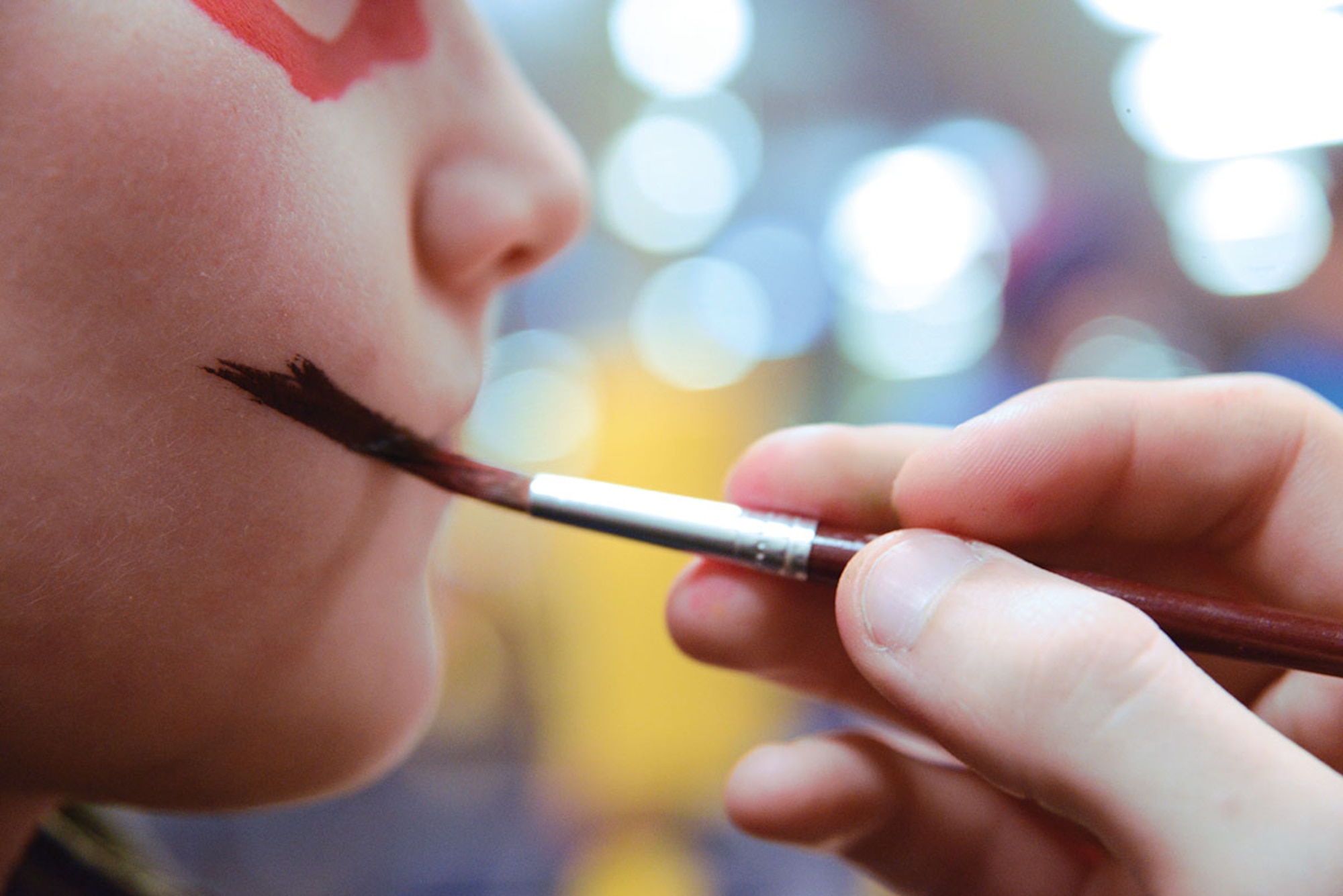 A volunteer gives a child a face painting during Breakfast with Santa at the Arctic Oasis at Joint Base Elmendorf-Richardson, Alaska, Dec. 12, 2015. The Arctic Oasis provided a breakfast, crafts, face painting, a photo booth and photo opportunity with Santa. (U.S. Air Force photo by Airman 1st Class Christopher R. Morales)