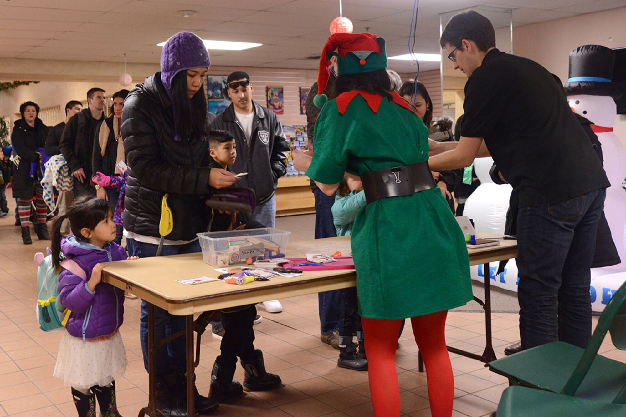 Families pay for breakfast and many festive activities during Breakfast with Santa at the Arctic Oasis at Joint Base Elmendorf-Richardson, Alaska, Dec. 12, 2015. Breakfast with Santa provided a breakfast, crafts, face painting, a photo booth and photo opportunity with Santa. (U.S. Air Force photo by Airman 1st Class Christopher R. Morales)