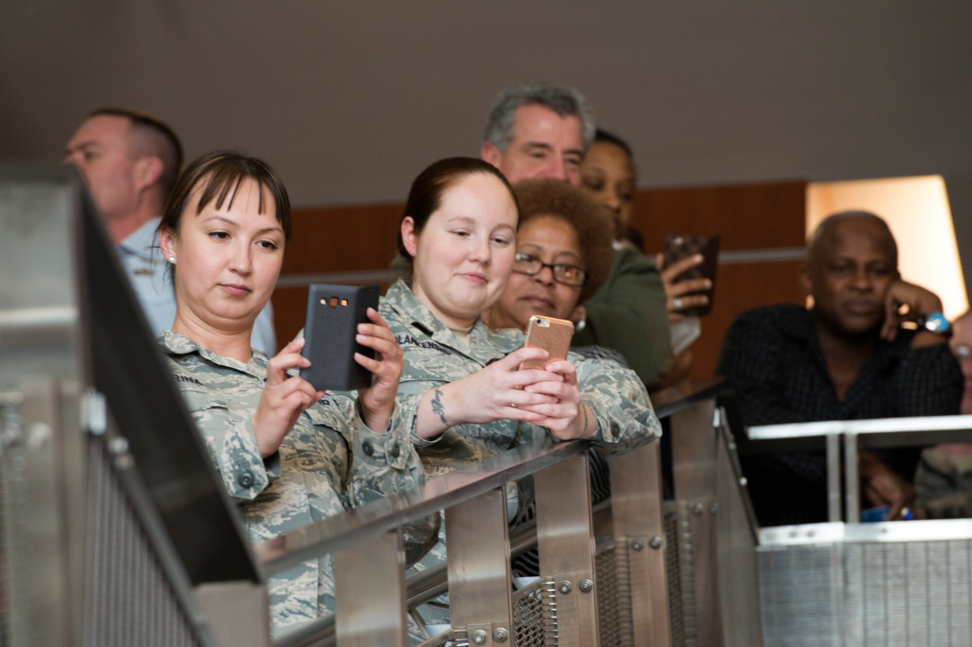 Military members and civilians take video of the U.S. Air Force Band’s Max Impact during a surprise performance in the lobby of the William A. Jones III building at Joint Base Andrews, Md., Dec. 16, 2015. Max Impact performed to spread holiday cheer through the building. (U.S. Air Force photo by Airman 1st Class Philip Bryant/Released)