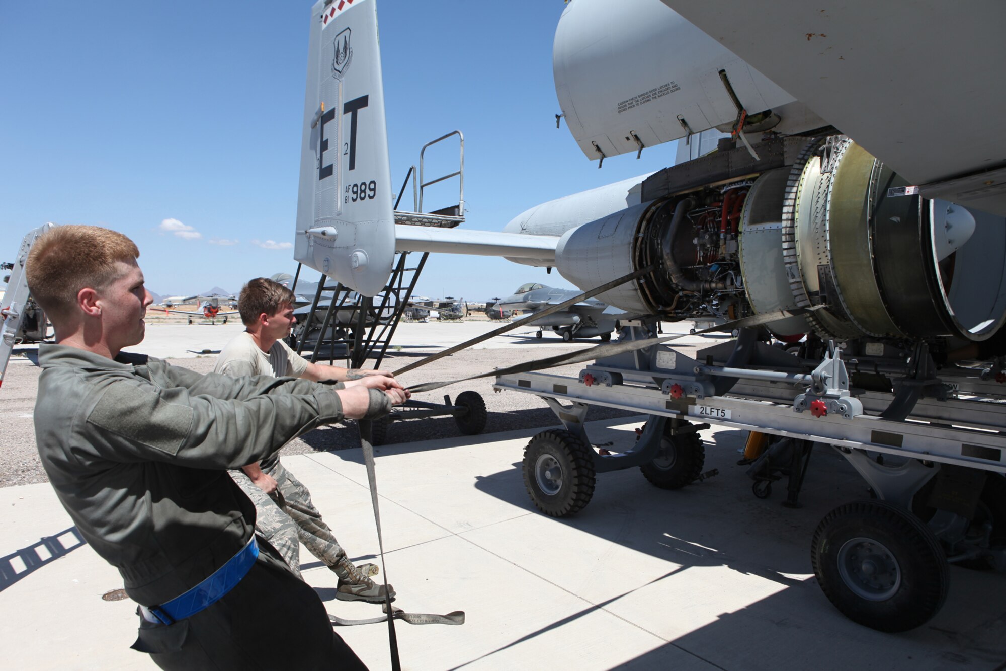Airman 1st Class Nathan Dunn, front, and Senior Airman Joshua Anderson, both assigned to the 355th Maintenance Group at Davis-Monthan AFB, Ariz. steady the A-10 motor as it is removed and placed on a transport. (U.S. Air Force photo by Terry Pittman)
