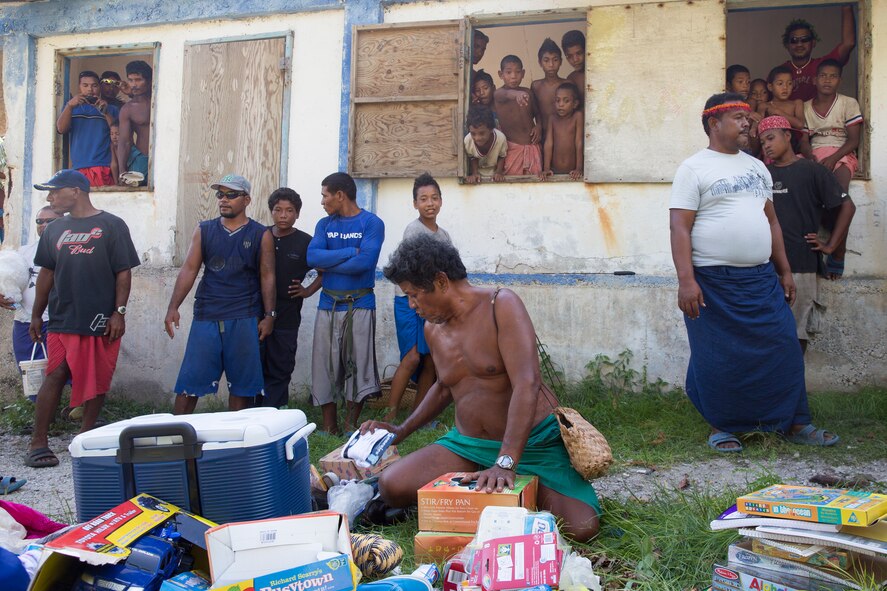 Island children look on with excitement as Louis Man6gtau, Chief of Fais Island, sorts through supplies and gifts that were dropped during Operation Christmas Drop 2015, Dec. 8, 2015, at Fais Island, Federated States of Micronesia. Operation Christmas Drop is a humanitarian/disaster relief training event where C-130 crews provide critical supplies to 56 islands throughout the Commonwealth of the Northern Marianas, Federated States of Micronesia and Republic of Palau. This year marks the first ever trilateral execution that includes air support  where the U.S. Air Force, Japan Air Self-Defense Force and the Royal Australian Air Force.(U.S. Air Force photo by Osakabe Yasuo/Released)