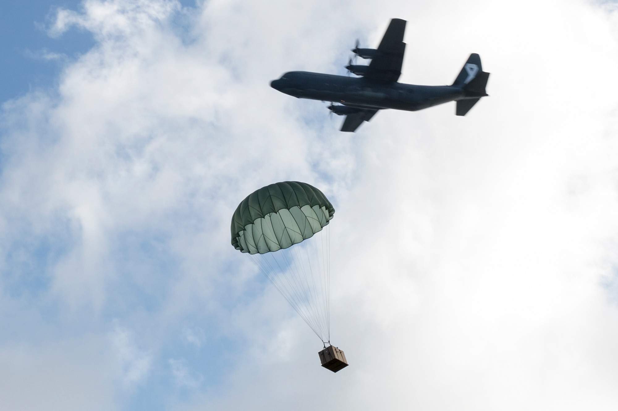 Royal Australian Air Force C-130J aircrew observe a U.S. Air Force C-130H low-cost, low-cost altitude bundle drop to Fais Island, Federated States of Micronesia, Dec. 8, 2015, during Operation Christmas Drop 2015. Airmen delivered over 800 pounds of supplies to the island of Fais during the drop. This year marks the first trilateral Operation Christmas Drop where the U.S. Air Force, Japan Air Self-Defense Force and RAAF work together to provide critical supplies to 56 Micronesian islands impacting 20,000 islanders. (U.S. Air Force photo by Osakabe Yasuo/Released)
