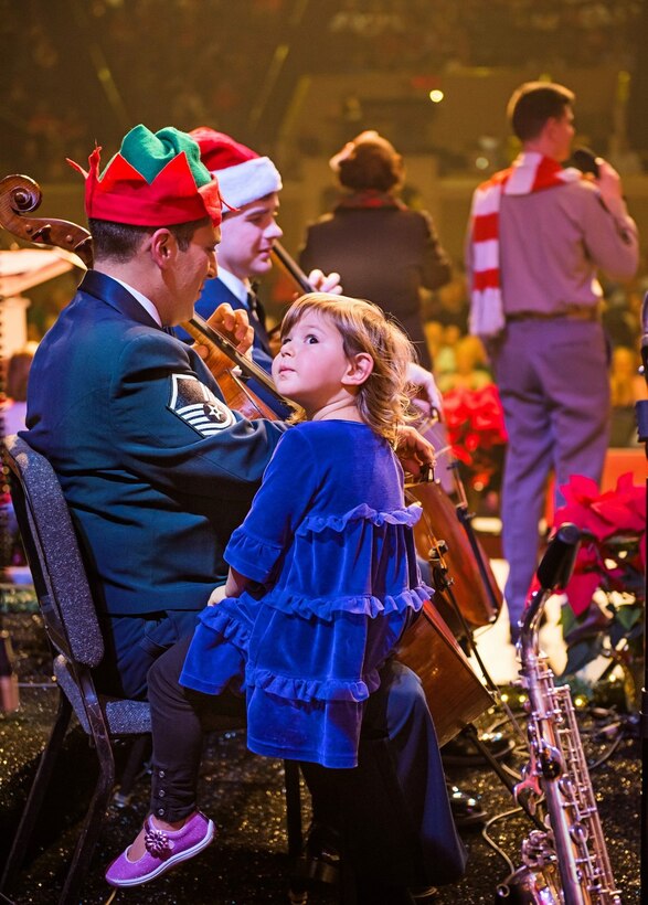 Master Sergeant Josh Kowalsky's daughter came up from the audience and hopped on her daddy's lap during the Christmas Carol Sing-a-long portion of The United States Air Force Band's Spirit of the Season performance at DAR Constitution Hall. (U.S. Air Force Photo by Senior Master Sgt Kevin Burns/released)