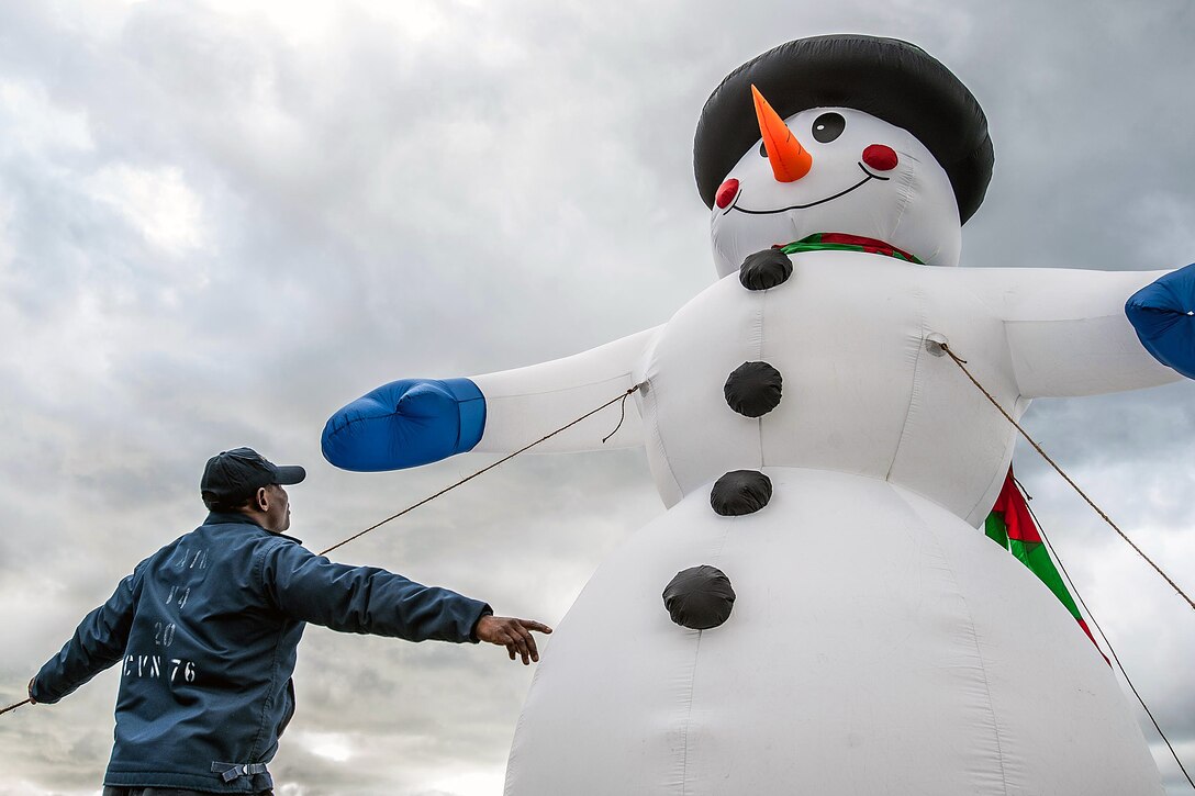 U.S. Navy Petty Officer 2nd Class Godson Bagnabana puts up an inflatable snowman on the flight deck of the USS Ronald Reagan in Yokosuka, Japan, Dec. 17, 2015. U.S. Navy photo by Petty Officer 3rd Class Nathan Burke