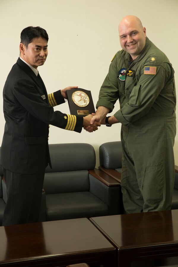 Japan Maritime Self-Defense Force Capt. Katsushi Ohkubo, commanding officer of Air Reconnaissance Squadron 81, presents Lt. Cmdr. Justin Gerle, officer in charge of Commander Task Group 72.5, Fleet Air Reconnaissance Squadron 1, with a token of friendship between the two squadrons at Marine Corps Air Station Iwakuni, Japan, Dec. 8, 2015. The two squadrons met for an annual unit exchange where they increased unit interoperability and built upon their current relationship.
