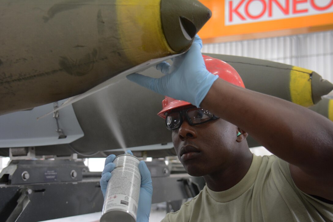 Senior Airman Christopher Haynesorth, 379th Expeditionary Maintenance Squadron Munitions Flight, sprays the serial number on a 2,000-pound joint attack direct munition at Al Udeid Air Base, Qatar Dec. 17. Haynesworth, a native of Richmond, Virginia, is part of a record-setting munitions team that has built nearly 4,000 bombs since July 2015. (U.S. Air Force photo by Tech. Sgt. James Hodgman/Released)