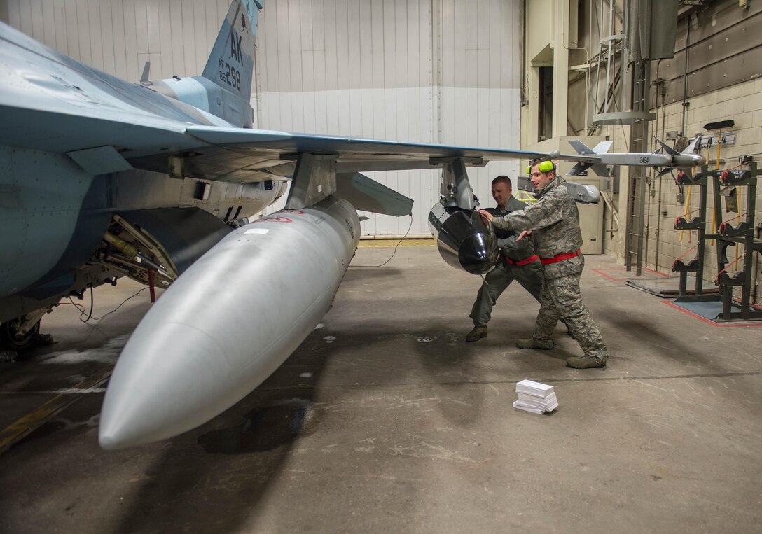 Air Force Staff Sgts. Robert Knickle, left, and Timothy Smith push luggage into a pod on an F-16 Fighting Falcon aircraft on Eielson Air Force Base, Alaska, Dec. 7, 2015. Knickle and Smith are crew chiefs assigned to the 354th Aircraft Maintenance Squadron. More than 30 maintenance airmen worked an early shift to help launch several jets to Tyndall Air Force Base, Fla., for Checkered Flag 16-1, a large-force exercise that simulates a deployed environment to cross-check weapons systems. U.S. Air Force photo by Staff Sgt. Shawn Nickel