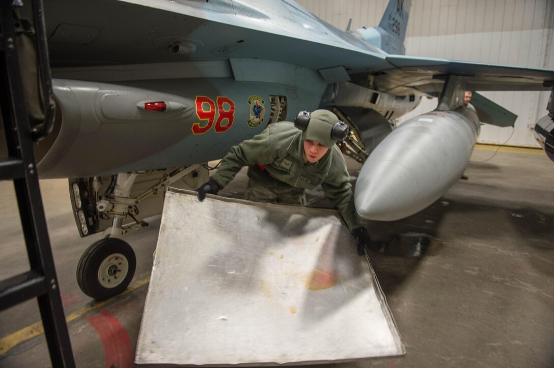 Air Force Airman 1st Class Andres removes a drip pan from under an F-16 Fighting Falcon aircraft on Eielson Air Force Base, Alaska, Dec. 7, 2015. Andres is a weapons journeyman assigned to the 354th Aircraft Maintenance Squadron. U.S. Air Force photo by Staff Sgt. Shawn Nickel