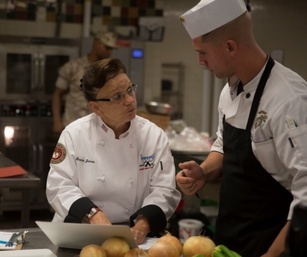 Emma James, left, a galley judge for the culinary competition, speaks to Sgt. Andrew Perkins, a Food Service Specialist with 1st Battalion, 8th Marine Regiment, about the competition aboard Camp Lejeune, N.C., Sept. 29, 2015. The Chef of the Quarter competition pits the finest chefs, both Marines and civilians, against one another to determine whose dish satisfies both the public’s choice and the judges.