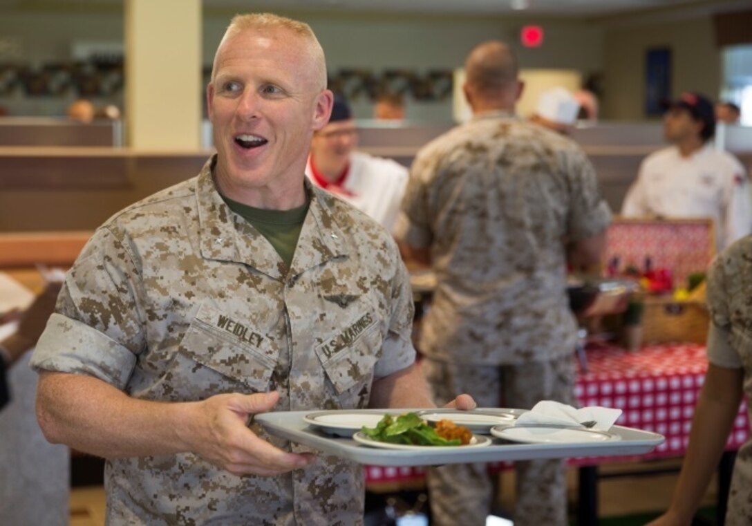 Brig. Gen. Thomas Weidley, the Commanding General for Marine Corps Installations-East, smiles as he receives food from one of the teams competing in the culinary competition aboard Camp Lejeune, N.C., Sept. 29, 2015. The Chef of the Quarter competition pits the finest chefs, both Marines and civilians, against one another to determine whose dish satisfies both the public’s choice and the judges.