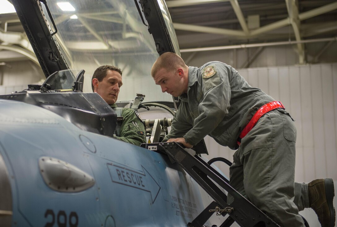 Air Force Staff Sgt. Robert Knickle, right, helps Lt. Col. Mark Sletten into an F-16 Fighting Falcon fighter aircraft on Eielson Air Force Base, Alaska, Dec. 7, 2015. Knickle is a crew chief assigned to the 354th Aircraft Maintenance Squadron and Sletten is an F-35 program integration officer. U.S. Air Force photo by Staff Sgt. Shawn Nickel