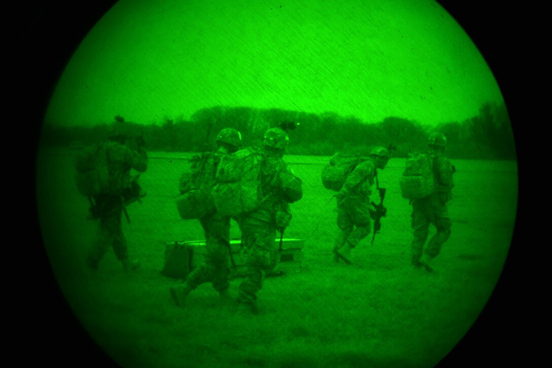 As seen through a night-vision device, U.S. Army paratroopers transport supplies after exiting a U.S. Air Force C-130 Hercules aircraft during Exercise Rock Nemesis on Rivolto Air Base, Italy, Dec. 4, 2015. U.S. Army photo by Paolo Bovo