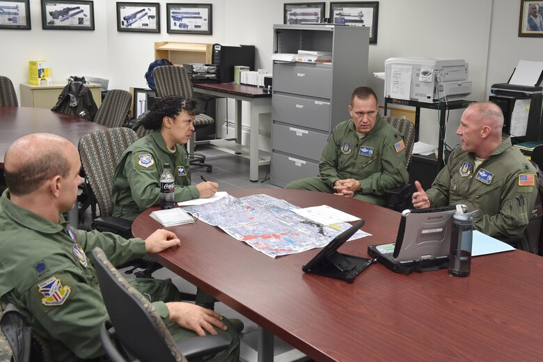 Lt. Col. Frank Galati, chief of standards and evaluation, Lt. Col. David Tancer, director of operations, and Lt. Col. Jeffrey Shaffer, aerial spray flight chief, all with the 757th Airlift Squadron, discuss the aerial spray mission at the 910th Airlift Wing with Maj. Gen. Stayce Harris, 22nd Air Force commander, here Dec. 5, 2015. Harris visited with 910th units during the December Unit Training weekend. (U.S. Air Force photo by Tech. Sgt. James Brock)