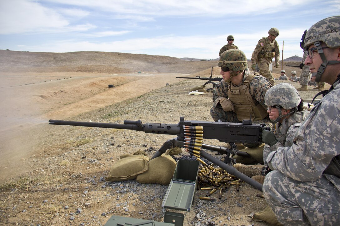 Wheeled vehicle mechanic Spc. Rowena Barrett, 1017th Quartermaster Company, 419th Combat Sustainment Support Battalion, engages targets 900 meters away during their weapons familiarization training at Camp Pendleton, Calif., Dec. 6, 2015. Marine Sgt. Spencer Smith, 5th Regiment Training Center, instructs Barrett on how to safely use the M2A1 .50-caliber machine gun.