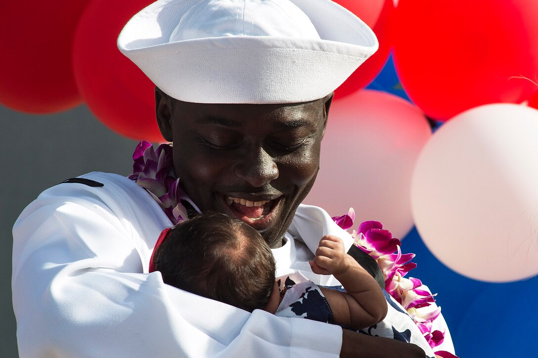 Navy Petty Officer 2nd Class Komla Amewouame meets his daughter for the first time after returning to Pearl Harbor, Hawaii, Dec. 17, 2015. Amewouame is assigned to the USS Chafee which returned from a seven-month deployment . U.S. Navy photo by Petty Officer 2nd Class Laurie Dexter