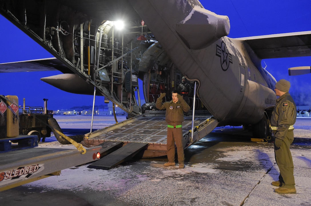Air Force Senior Airmen Chris Eggleston, center, guides a truck while loading gear belonging to Marines onto a C-130 Hercules aircraft in support of Toys for Tots on Joint Base Elmendorf-Richardson, Alaska, Dec. 8, 2015. Eggleston is a crew chief assigned to the Alaska Air National Guard's 144th Airlift Squadron. U.S. Air Force photo by Alejandro Pena