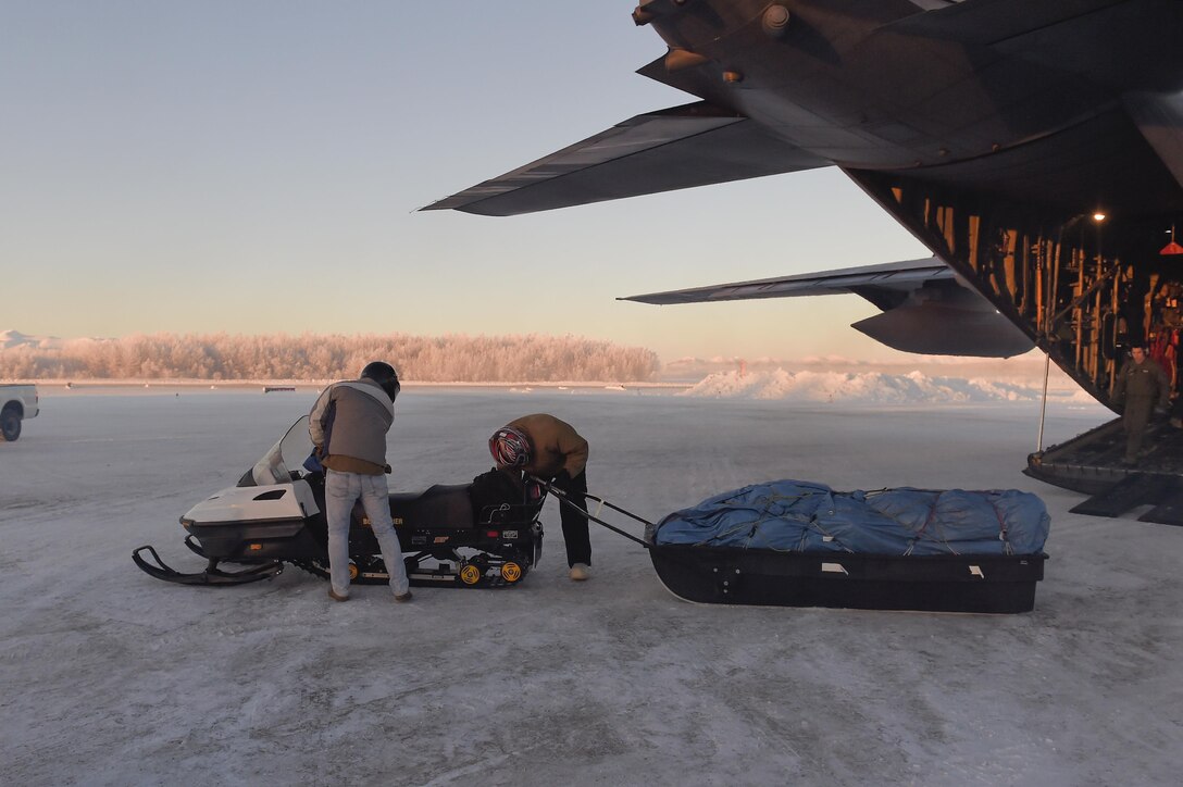 Marine Corps Sgt. Mauricio Sandoval, left, and Master Gunnery Sgt. Jason Milbery offload a snow machine and sled from a C-130H Hercules aircraft before conducting Toys for Tots in McGrath, Alaska, Dec. 8, 2015. Sandoval and Milbery are assigned to Delta Company, 4th Law Enforcement Battalion and 2nd Maintenance Battalion. U.S. Air Force photo by Alejandro Pena