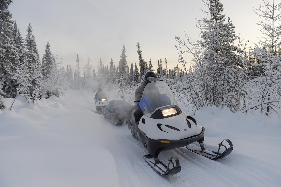 Marine Corps Sgt. Mauricio Sandoval, front, and Master Gunnery Sgt. Jason Milbery, drive snowmobiles between McGrath and Takotna, Alaska, during Toys for Tots, Dec. 10, 2015. Sandoval and Milbery are assigned to Delta Company, 4th Law Enforcement Battalion and 2nd Maintenance Battalion. U.S. Air Force photo by Alejandro Pena  