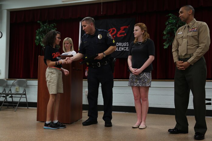 Police officer Chris Stephens, left, Emily Gayle, center, and Maj. Eduardo Pinales present a student a certificate during a Drug Abuse Resistance Education graduation at Laurel Bay Dec. 16. The fifth grade students of Bolden Elementary completed a 10-week curriculum with Stephens, teaching them decision making skills about challenging situations. Stephens is the school resource officer for the Laurel Bay schools, Gayle is the South Carolina D.A.R.E. youth advisor, and Pinales is the Provost Marshal aboard Marine Corps Air Station Beaufort.