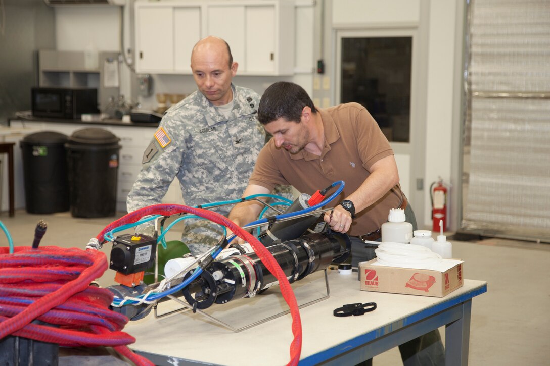 During COL Aguilar's visit to ERDC CHL's Soils Lab, David Perkey demonstrates the River-PICS system, an integrated settling column, laser diffraction grain size analyzer, and CTD probe. The system was recently used to monitor suspended sediment size and settling rates in the salt wedge in the lower MS River.