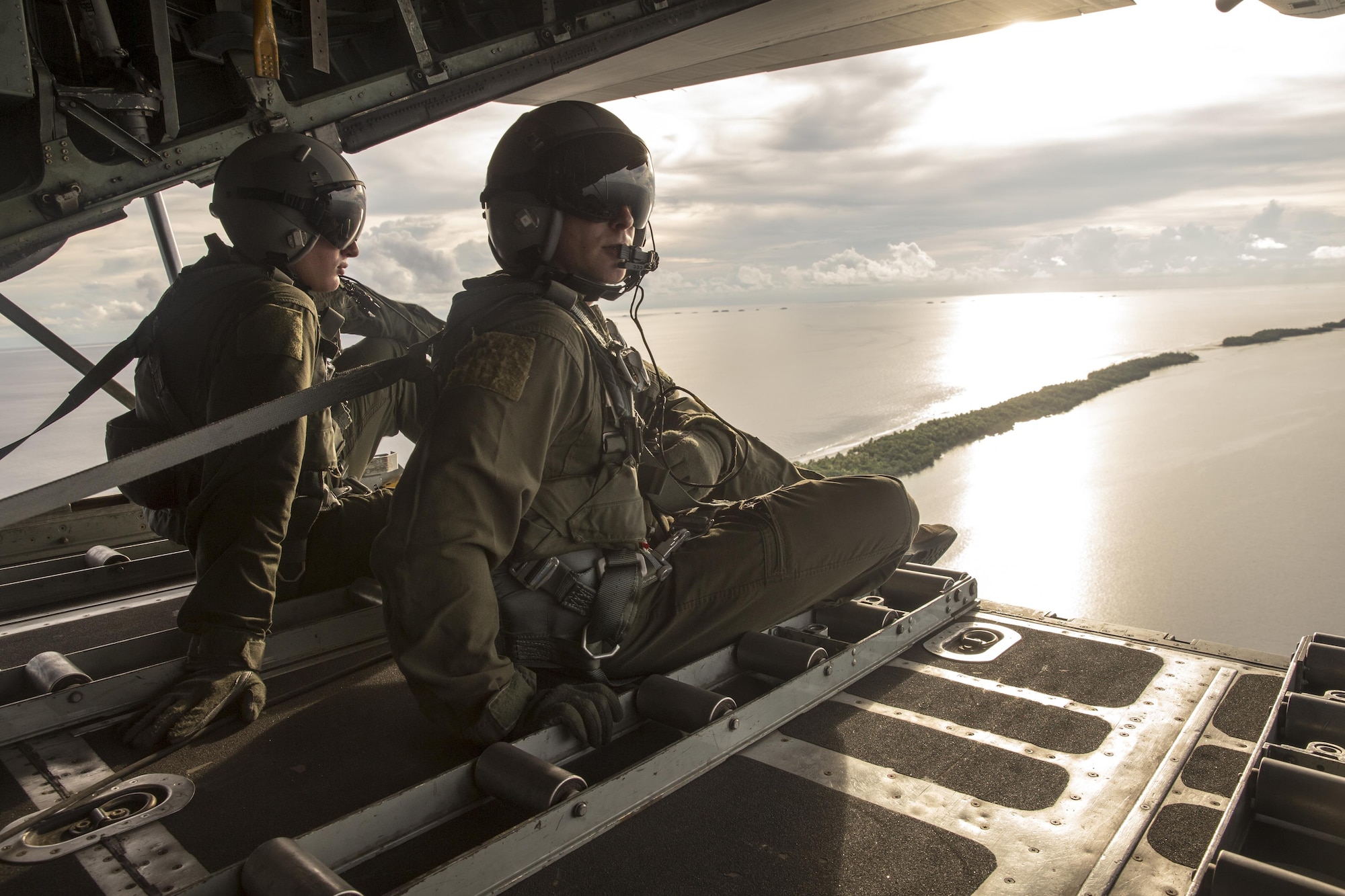 (Right to left) Staff Sgt. Ren Forbes and Airman 1st Class Alexander Lauher, 36th Airlift Squadron loadmasters, watch out the back of a C-130H Hercules after delivering eight bundles to Mortlock Islands, Federated States of Micronesia, Dec. 9, 2015, during Operation Christmas Drop. Every December, C-130H Hercules aircrews from Yokota head to Andersen Air Force Base to execute low-cost, low-altitude humanitarian airdrops to islanders throughout the Commonwealth of the Northern Marianas, Federated States of Micronesia, Republic of Palau. These islands are some of the most remote locations on the globe spanning a distance nearly as broad as the continental U.S. It is the longest-running Department of Defense humanitarian airdrop operation with 2015 being the first trilateral execution with support from Japan Air Self-Defense Force and Royal Australian Air Force. (U.S. Air Force photo by Osakabe Yasuo/Released)