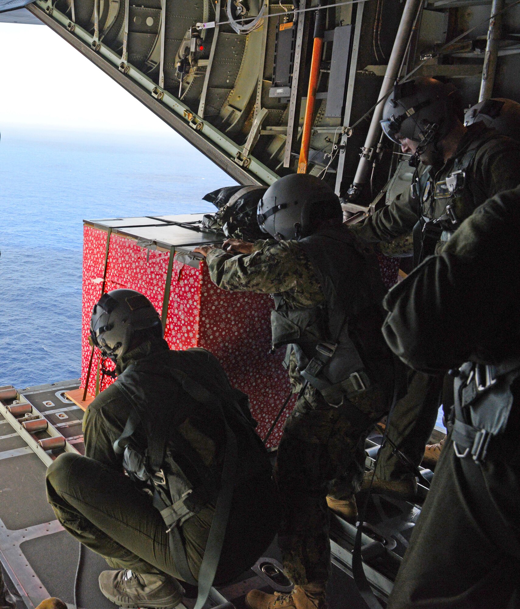 Loadmasters from the 36th Airlift Squadron, Yokota Air Base, push a low-cost low-altitude bundle from the back of a C-130H during Operation Christmas Drop, Dec. 8, 2015. This is the first trilateral Operation Christmas Drop where the U.S. Air Force, Japan Air Self-Defense Force and Royal Australian Air Force will work together to provide critical supplies to 56 Micronesian islands impacting 20,000 people covering 1,000 by 1,800 nautical miles while training for regional humanitarian aid and disaster response. (U.S. Air Force photo by Tech. Sgt. Melissa K. Mekpongsatorn)