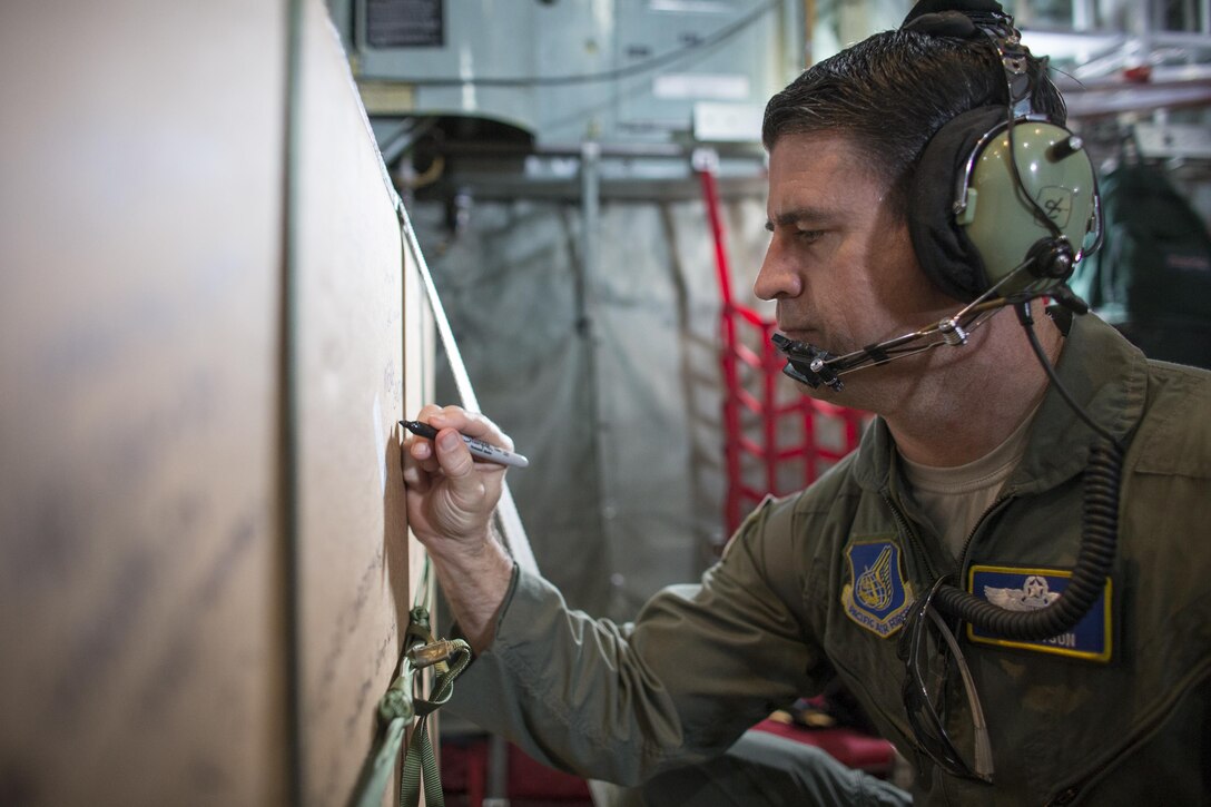 Col. Robert Dotson, 374th Operations Group commander, writes a holiday greeting to the recipients of one of the boxes packed in support of Operation Christmas Drop, Dec. 9, 2015. This year marks the first ever trilateral Operation Christmas Drop where the U.S. Air Force, Japan Air Self-Defense Force and the Royal Australian Air Force work together to provide critical supplies to 56 islands, impacting 20,000. (U.S. Air Force photo by Osakabe Yasuo/Released)