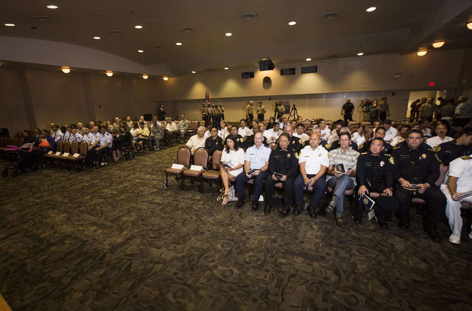 Military and civilian personnel take their seats before the First Responder Recognition Ceremony begins at the Neal S. Blaisdell Center, in Honolulu, Dec. 18, 2015. The first responders aided in the rescue and treatment of the crew and passengers of a 15th Marine Expeditionary Unit MV-22 Osprey tilt-rotor aircraft, which suffered a mishap at Marine Corps Training Area Bellows on May 2015.