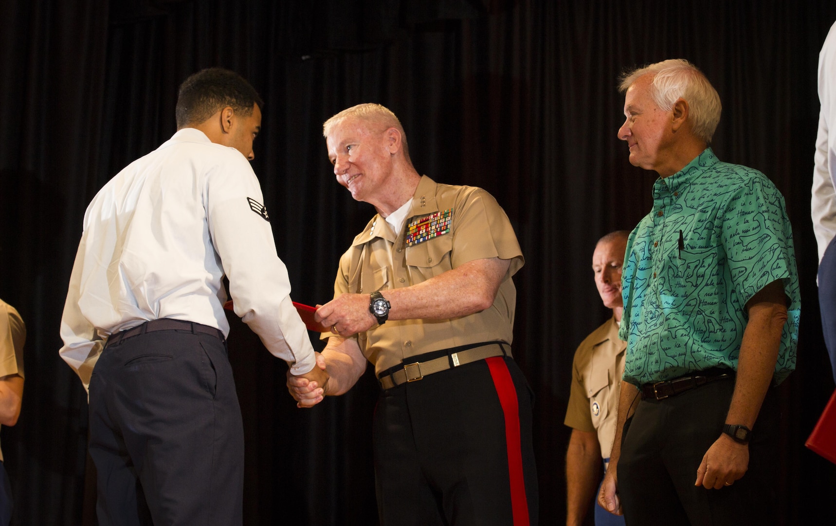 U.S. Air Force Senior Airman Marcus Griffin (left), receives an award from Lt. Gen. John A. Toolan (middle), commander, U.S. Marine Corps Forces, Pacific, and Mayor Kirk Caldwell (right), City & County of Honolulu, during the First Responder Recognition Ceremony at the Neal S. Blaisdell Center, in Honolulu, Dec. 18, 2015. Military and civilian personnel that selflessly assisted during the rescue and treatment of the Marines and Sailor received recognition from the U.S. Marine Corps Forces, Pacific Commander.