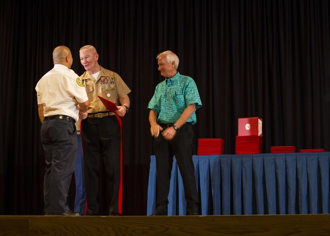 Chief Damien Kahaulelio (left), Honolulu Fire Department, Battalion, 3/1,  receives an award from Lt. Gen. John A. Toolan (middle), commander, U.S. Marine Corps Forces, Pacific, and Mayor Kirk Caldwell (right), City & County of Honolulu, during the First Responder Recognition Ceremony at the Neal S. Blaisdell Center, in Honolulu, Dec. 18, 2015. Various individuals from the Honolulu Emergency Services Department, Honolulu Fire Department, and Honolulu Police Department were recognized for their heroic, selfless actions while responding to a mishap involving an MV-22 tilt-rotor aircraft.