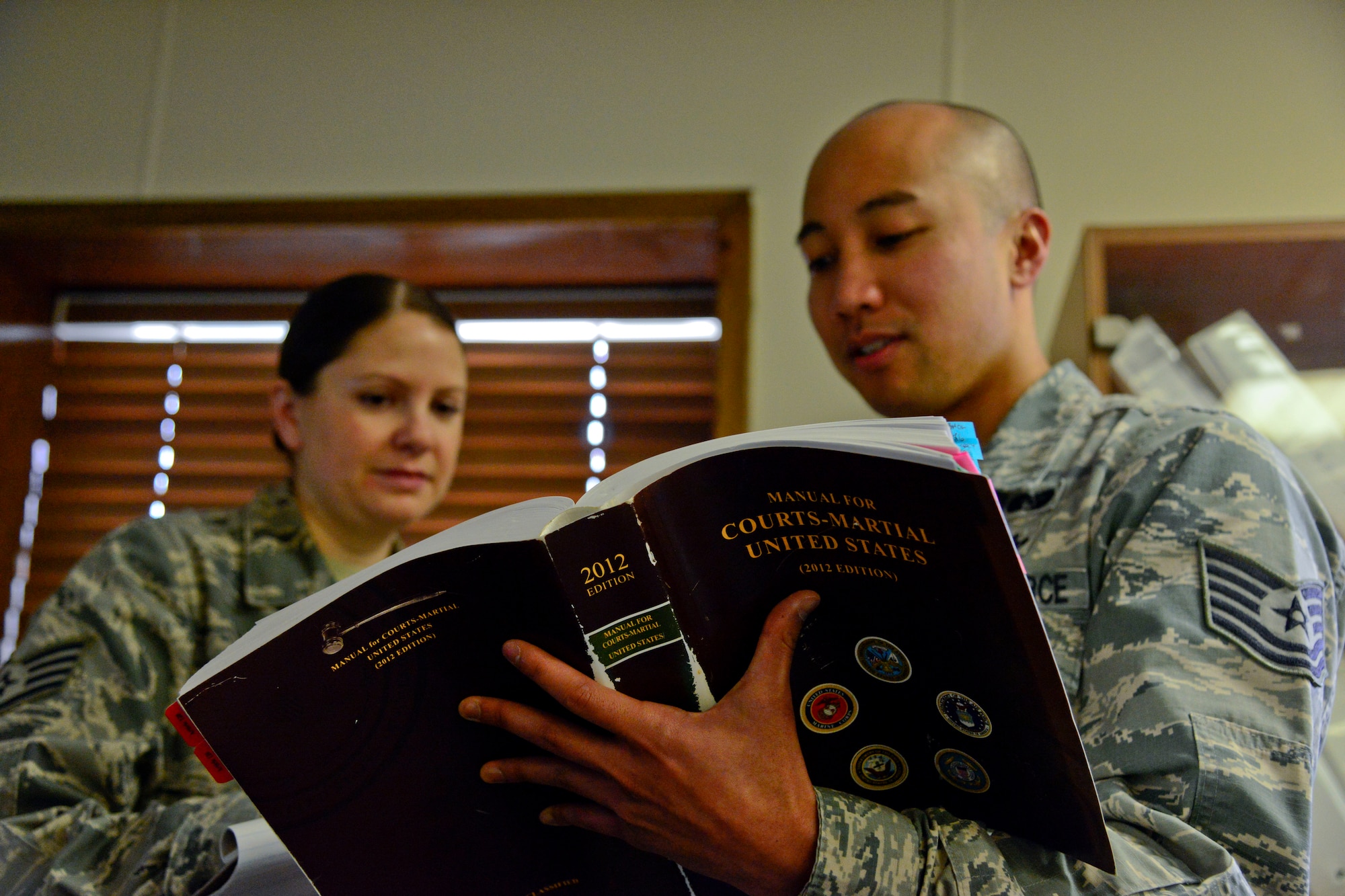 Staff Sgt. Barbara Coddington and Tech. Sgt. Angelo Macugay, 51st Fighter Wing judge advocate military justice paralegals, look through the Manual for Courts Martial in the legal office on Osan Air Base, Republic of Korea, Dec. 15, 2015. Paralegals use the manual to understand elements of crimes and punishments for specific charges, apprehension for pre-trial restraint and Uniform Code of Military Justice articles. All Defense Department paralegals utilize the manual. (U.S. Air Force photo/Senior Airman Kristin High)