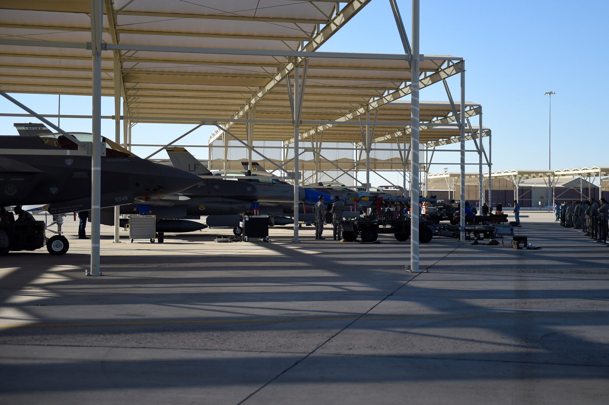 Weapons load crew members from the 61st Aircraft Maintenance Unit, 309th AMU, 310th AMU, and the 425th AMU compete during the 4th quarter weapon's loading competition Dec. 18 at Luke Air Force Base, Ariz. This quarter featured the first time the F-35 was used in the competition against the F-16 Fighting Falcon at Luke. (U.S. Air Force photo by Staff Sgt. Staci Miller)