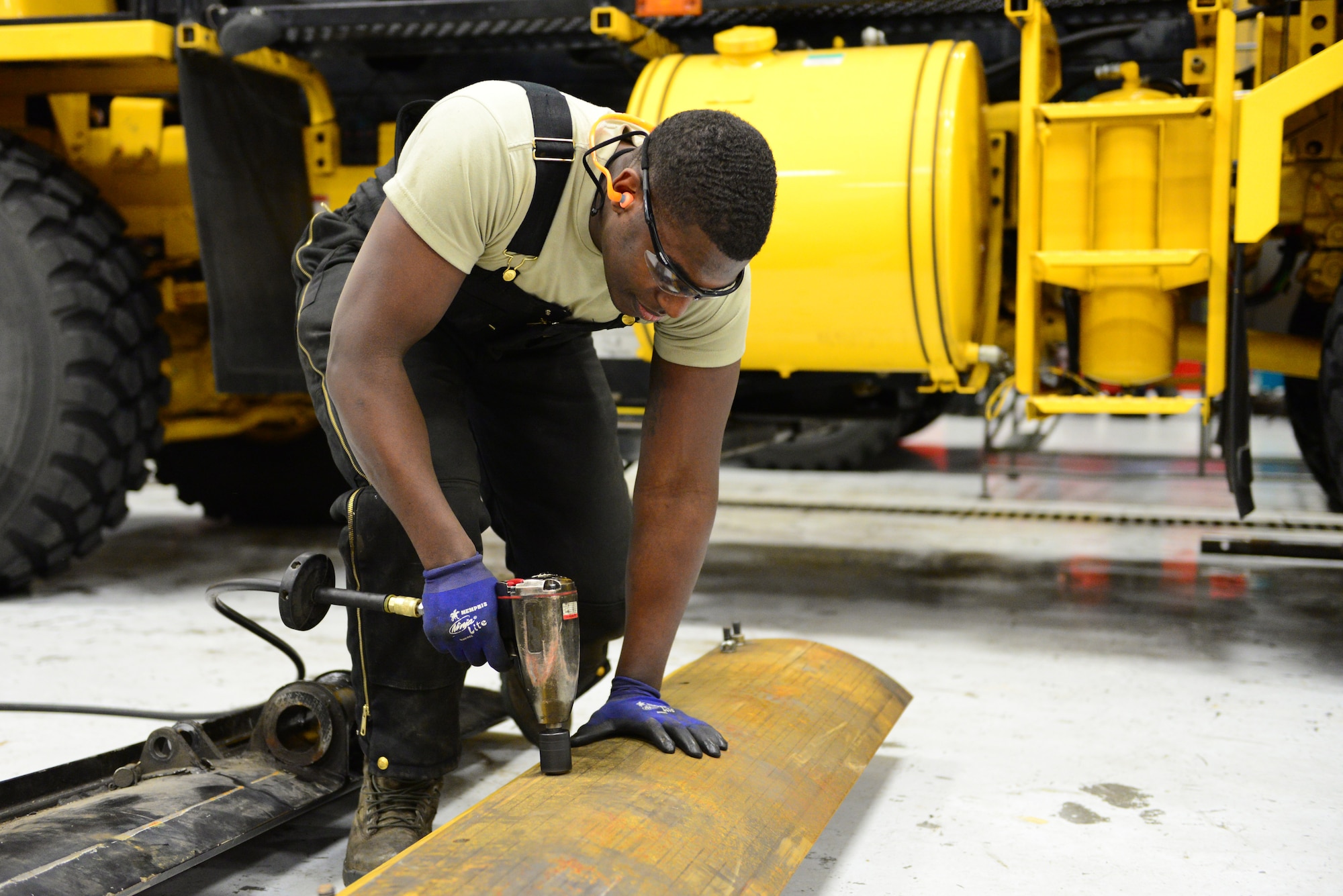 U.S. Air Force Senior Airman Dion Edwards, a 354th Logistics Readiness Squadron vehicular equipment maintenance mechanic, uses an impact wrench Dec. 16, 2015, at Eielson Air Force Base, Alaska. Edwards is tightening the bolts on the cutting edge of an Oshkosh scraper. (U.S. Air Force photo by Airman 1st Class Cassandra Whitman/Released)