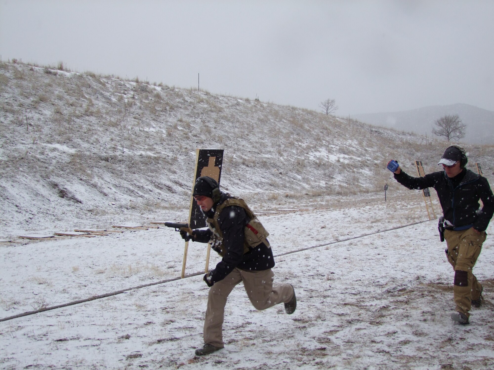 A cadet on the U.S. Air Force Academy's Combat Shooting Team (left) runs through a simulating firing event at the Academy's firing range, Dec. 5, 2015. First Lt. Dalton Bridgers (right), a member of the Air Force Shooting Team, led the CST members through a day of drills to enhance their skills before a Dec. 6, 2015 competitive firing event in Aurora, Colo. (U.S. Air Force photo)