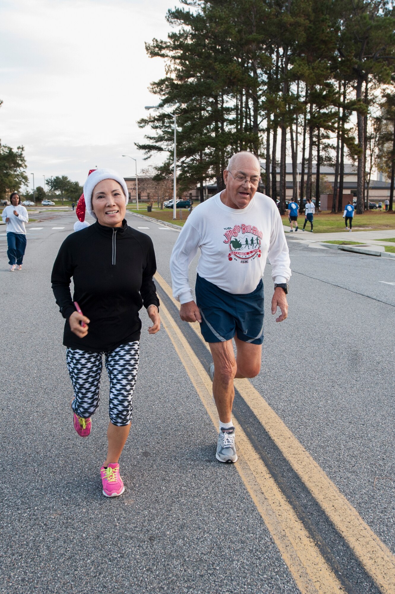 Sun Cha Marcotte and Joe Christian, 5K participants, run towards the finish line during the Santa 5k, Dec. 18, 2015, at Moody Air Force Base, Ga. This is Christian's 1,114th run since his retirement from the Air Force in 1979. (U.S. Air Force photo by Airman 1st Class Lauren Johnson/Released)