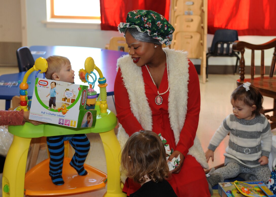 Mrs. Claus smiles as a child enjoys his present during the annual Angel Tree program at the Youth and Family Services Center in Rapid City, S.D., Dec. 17, 2015. YFS is the largest human services organization of its kind in western South Dakota. (U.S. Air Force photo by Airman 1st Class Denise M. Nevins/Released)