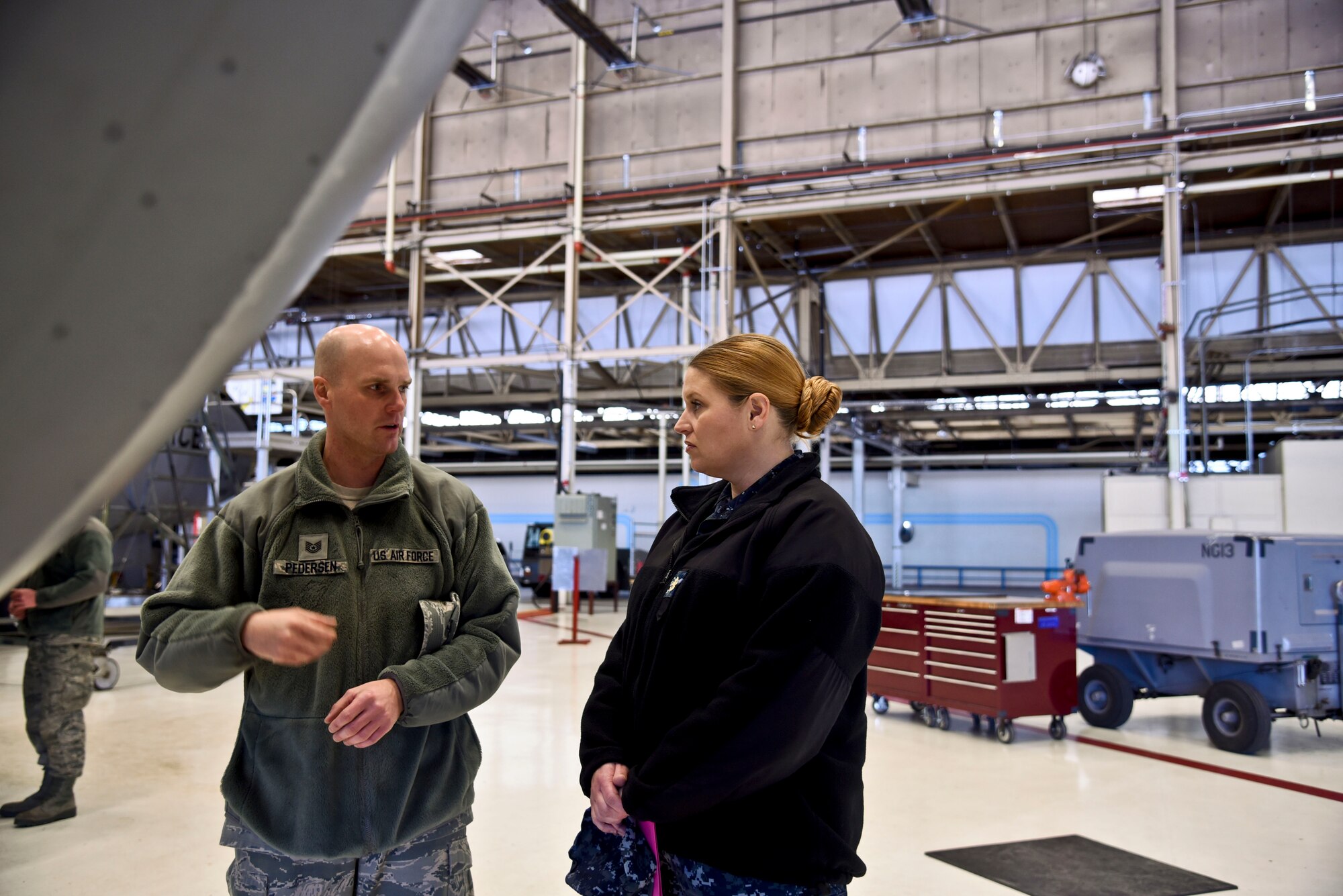 Tech Sgt. Christopher Pedersen, 92nd Air Refueling Wing executive assistant to the command chief, explains parts of the KC-135 Stratotanker to Chief Petty Officer Laura L. McDonald, Navy Operations Support Center Spokane Spokane senior enlisted leader, and her commanding officer during a tour of Fairchild Air Force Base, Wash., Dec. 16, 2015.  NOSC Spokane leadership had the opportunity to see daily operations and review the resources available per the Host Area Agreement, fostering the relationship between the Air Force and Navy agencies to improve personnel quality of life. (U.S. Air Force photo/Airman 1st Class Taylor Bourgeous)